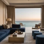 Al Marjan Island apartment lounge at dusk with a navy velvet sofa, brass coffee table, table lamp and terrace facing the sea